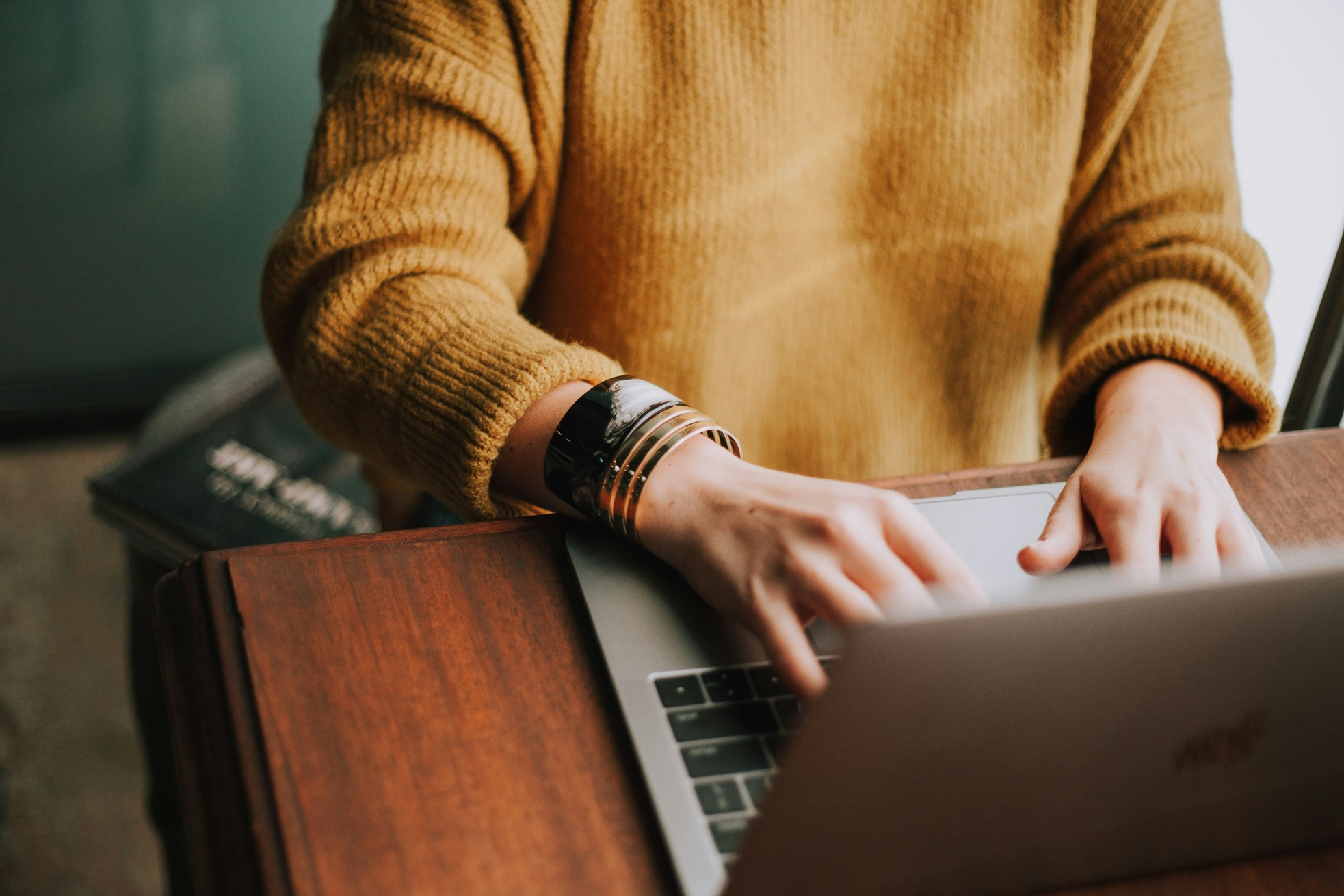 Person in orange shirt using a laptop while applying for payday loans online