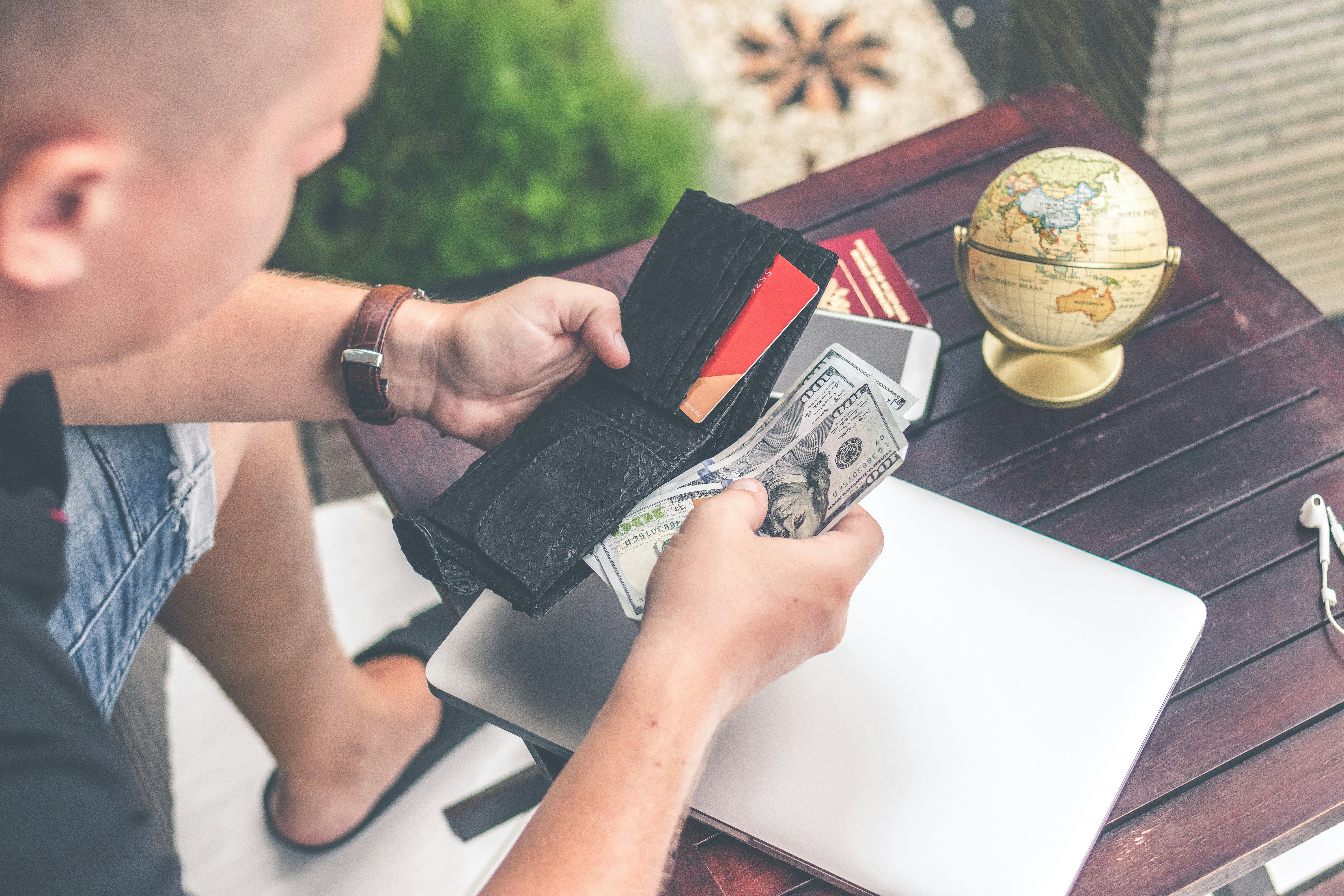 Person holding wallet and US dollar bills at table